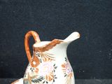 a small vase with a handle sitting on a black surface