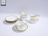 quatre tasses à café blanches et dorées avec leurs soucoupes, posées sur une surface blanche