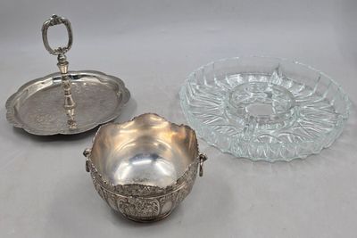 deux plats en métal argenté et un saladier en verre posés sur une table