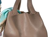 un sac à main en cuir marron posé sur une boîte orange, à côté d'une écharpe bleue et blanche