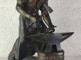 bronze statue of a blacksmith with a hammer and an anvil