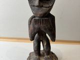 une vieille statue en bois représentant un homme tenant un peigne dans ses mains