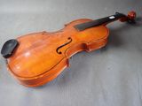 an old violin sitting on top of a table next to a piece of wood