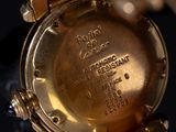 a close up of a gold watch with a chain around it