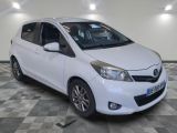 the white toyota yaris is parked on a checkered tile floor