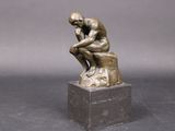 une statue en bronze d'un homme assis sur un rocher