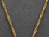 a close up of a necklace with a gold chain on a black surface