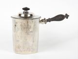 une vieille casserole en argent avec une poignée en bois posée sur une surface blanche