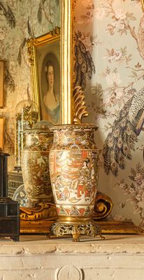 une photo d'une cheminée sur laquelle sont posés une horloge et des vases