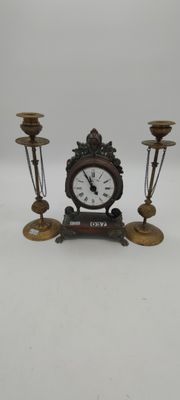 a clock that is sitting on a table with three candles