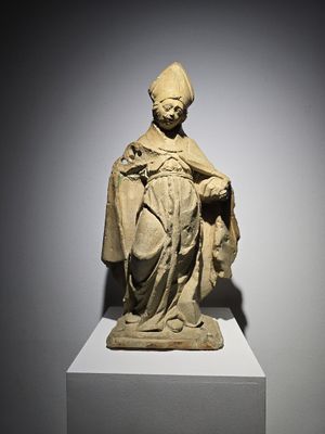 a statue of a man with a hat and robe on a pedestal