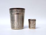 two silver cups sitting next to each other on a white surface