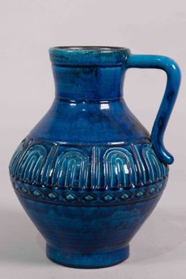 un vase bleu muni d'une anse, posé sur une table