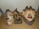 trois masques en bois posés les uns à côté des autres sur une table