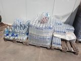 de nombreuses bouteilles d'eau posées sur une palette près d'un mur