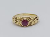 a gold ring with a ruby stone in the center