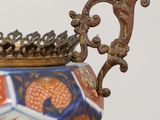 a close up of a vase on a stand with a crown on top