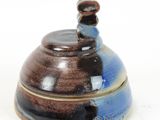 a brown and blue bowl with a lid on a white surface