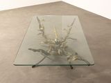 a glass table with a metal sculpture on it