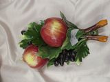 deux pommes sur une assiette, accompagnées de feuilles et de raisins