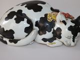 une figurine de vache noire et blanche couchée sur une table