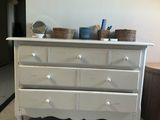 a picture of a dresser in a room with a painting on the wall
