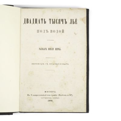 un vieux livre à la couverture noire posé sur une table blanche