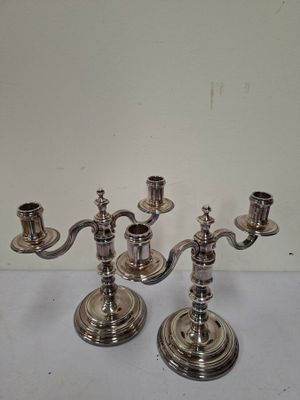 une paire de bougeoirs argentés posés sur une table blanche