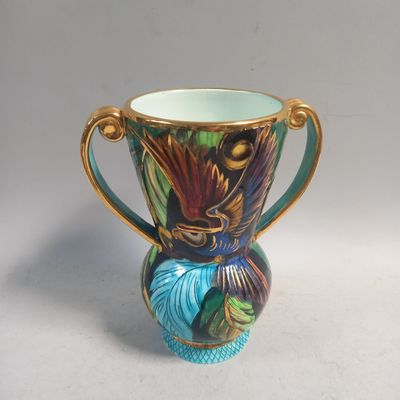 un vase coloré avec une anse dorée sur un fond blanc
