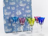 plusieurs verres à vin de différentes couleurs posés devant une boîte bleue