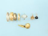 many different types of rings and earrings laid out on a blue surface