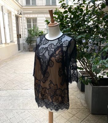 une robe en dentelle noire posée sur un mannequin devant un immeuble