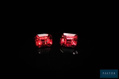 une paire de boucles d'oreilles rouges lumineuses posées sur une surface noire