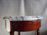 a marble top on a wooden stool in front of a gray wall
