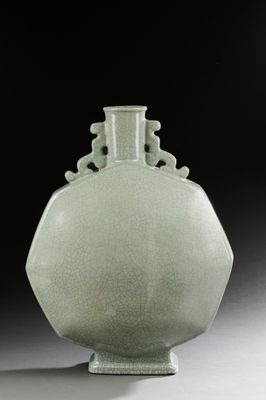un vase vert posé sur une table sur fond noir