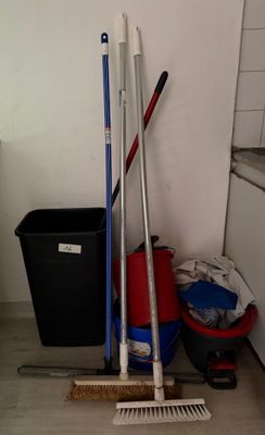 des balais, une serpillière, des seaux et une poubelle dans une cuisine