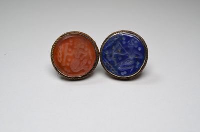 two rings with blue and orange stone in them on a white surface