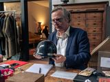 un homme assis à un bureau, tenant une clochette à la main