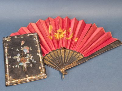 un éventail rouge et un livre posés sur une surface bleue