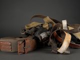 a pile of old leather belts on a black background