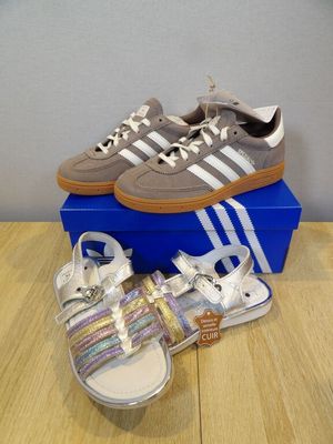 adidas shoes and sandals on a table next to a blue box