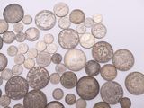 a pile of old silver coins on a white surface