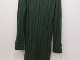 the sweater is green and is hanging on a hanger on the wall