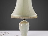une lampe de table blanche surmontée d'un abat-jour beige