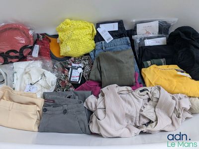 a bath tub filled with lots of clothes and a teddy bear