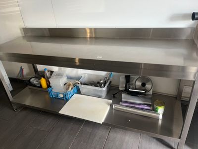 une table en acier inoxydable sur laquelle est posée une planche à découper