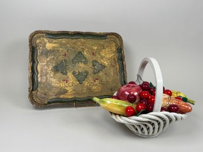 une corbeille de fruits posée à côté d'un plateau orné d'une image