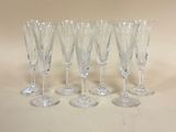 six verres à vin transparents sont alignés sur une surface blanche
