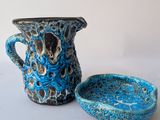 a blue pitcher and a bowl on a white table