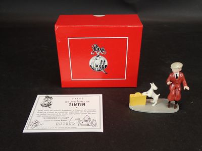 une petite figurine représentant un homme et un chien devant une boîte rouge